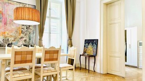 Een kamer met een eettafel, stoelen, een schilderij aan de muur en een deur.
