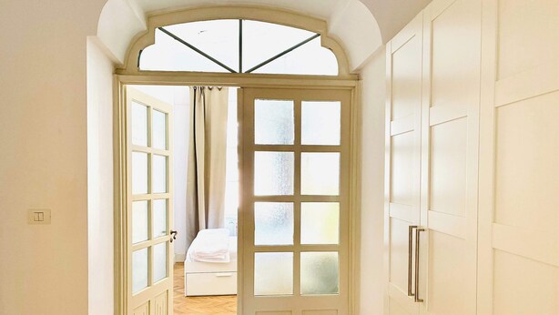 Een hal met een deur naar een slaapkamer, een bed en een kledingkast.