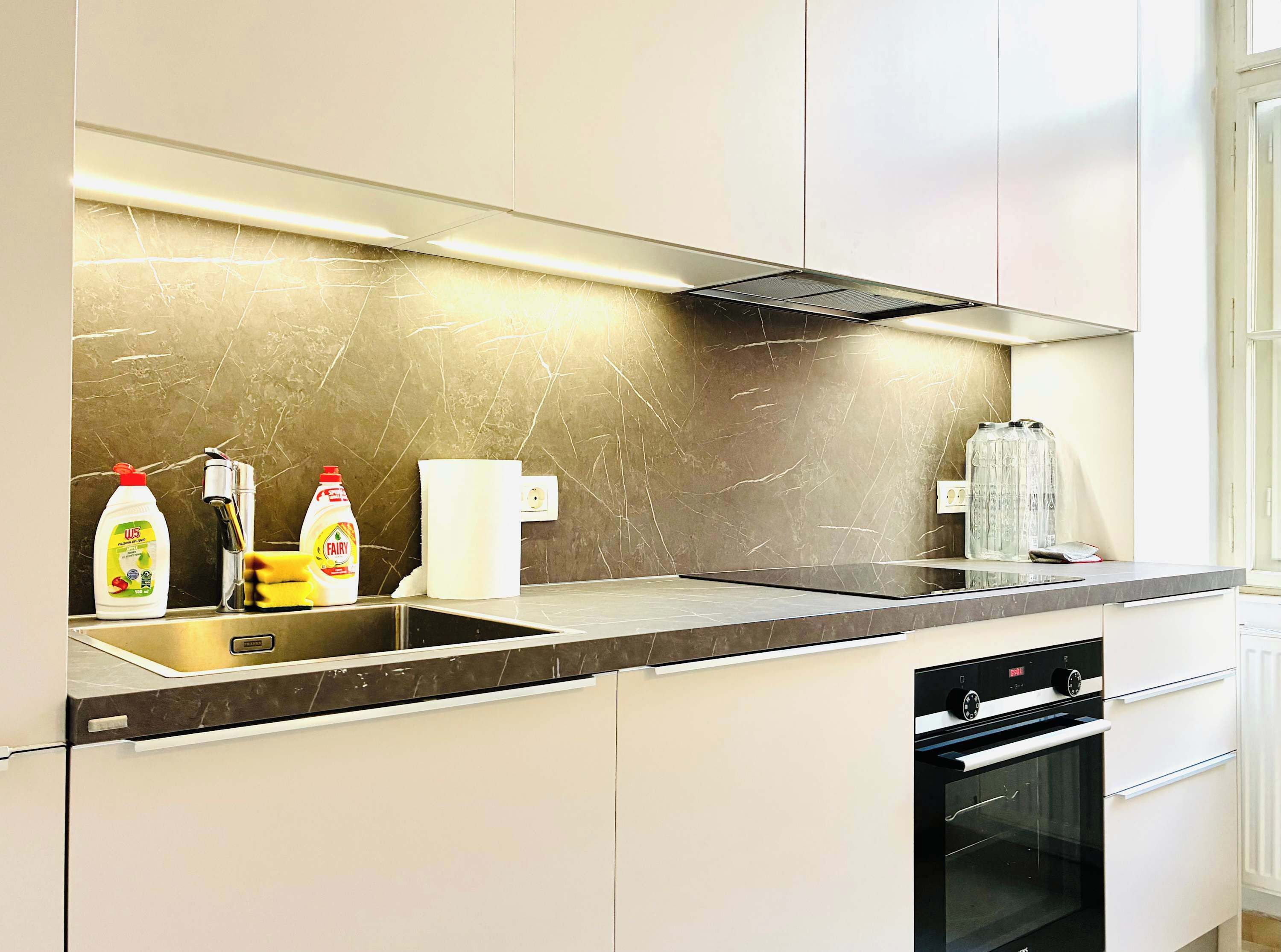A modern kitchen with a stainless steel sink, a dishwasher, and an oven.