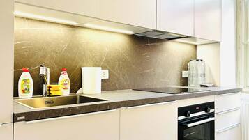 A modern kitchen with a stainless steel sink, a dishwasher, and an oven.