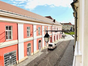A cobblestone street with red and white buildings, a white van parked on the street, and a person walking. - Joy City Stay  Unirii 4 (Timișoara)