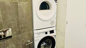 Une petite salle de bain équipée d’un lave-linge, de toilettes et d’un sol carrelé.