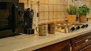 Een keuken met een koffiezetapparaat, een waterkoker, een fles en een mok op het aanrecht.