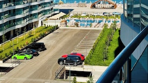 A modern hotel with a pool area, a view of the sea, and a parking lot with cars. - Hubix Suites | Superb View | Casa del Mar C2-80 (Mamaia)