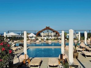 A pool area with lounge chairs, umbrellas, and a decorative archway. - Hubix Suites - Casa del Mar C2 2 (Mamaia)