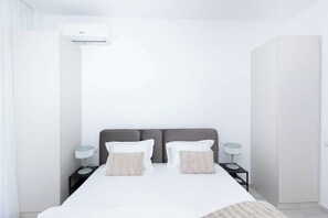 A modern bedroom with a bed, two bedside tables, and an air conditioning unit. - Hubix Suites - Casa del Mar C2 2 (Mamaia)