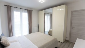 Una camera d'albergo moderna con un letto grande, uno specchio, un armadio e un termosifone.