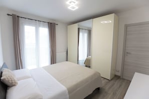 Une chambre d’hôtel moderne avec un grand lit, un miroir, une armoire et un radiateur.