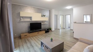 Un soggiorno moderno con una TV a schermo piatto, mobili in legno, un tavolino da caffè e un divano.
