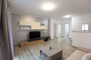Un salon moderne avec un téléviseur à écran plat, des meubles en bois, une table basse et un canapé.