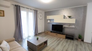 Un soggiorno moderno con divano, tavolino, televisore ed scaffali a muro.