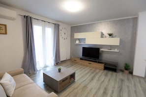 Un salon moderne comprenant un canapé, une table basse, un téléviseur et des étagères intégrées.