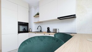 Une cuisine moderne avec des meubles blancs, une hotte noire, un four encastré et une machine à café.