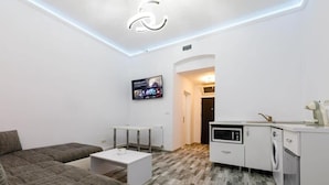 Un apartamento moderno con sala de estar, cocina y televisor montado en la pared.