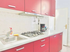 A kitchen with a gas stove, a coffee maker, and a sink.