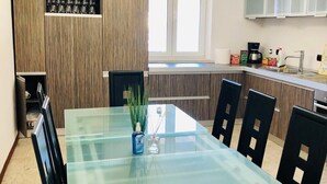 Une cuisine moderne avec une table à manger en verre, des chaises noires et des meubles de rangement en bois.