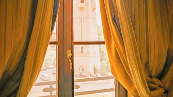 A window with curtains, a view of a building with a dome, and a street scene.