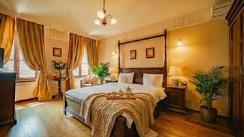 A four-poster bed with a canopy, a bedside table with a lamp, a potted plant, and a window with curtains.
