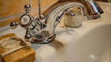 Ein Waschbecken mit einem Wasserhahn im Vintage-Stil, eine Seife und ein Glasbehälter.