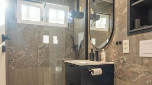 Une salle de bain moderne avec un mur en marbre, un meuble-lavabo noir, un miroir et une douche.