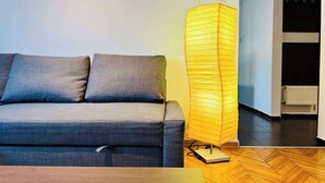 Ett modernt vardagsrum med en grå soffa, en hög golvlampa och ett soffbord i trä.