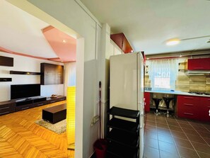 Een moderne keuken met een inbouwfornuis, rode kastjes en een eethoek met een houten vloer en een televisie.