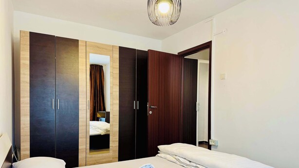 Ett hotellrum med en säng, två garderober, en spegel och en taklampa.
