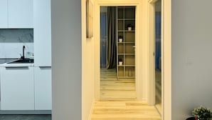Un couloir étroit, doté d’un plancher en bois, mène à une pièce dont la porte est coulissante.