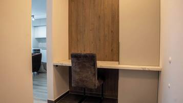 A small, modern kitchen with a wooden accent wall, a grey upholstered chair, and a white countertop.