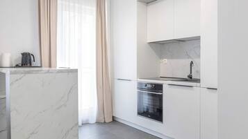 Een moderne keuken met witte kastjes, een inbouwoven en een roestvrijstalen spoelbak.