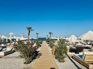 A beachside resort with lounge chairs, umbrellas, and a wooden pathway leading to the sea. - Hubix Suites | Superb View | Casa del Mar C2-78 (Mamaia)
