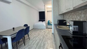 A compact hotel room with a kitchenette, a bed, a small seating area, and a dining table. - Joy City Stay Mangalia 5 (Timișoara)