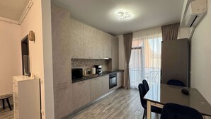A modern kitchen with a dining area, a refrigerator, a microwave, and a coffee machine. - Joy City Stay Mangalia 5 (Timișoara)
