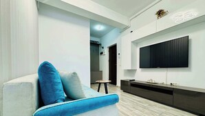A modern living room with a sofa, a flat-screen TV mounted on the wall, and a wooden floor. - Joy City Stay Mangalia 5 (Timișoara)