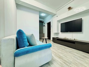 A modern living room with a sofa, a flat-screen TV mounted on the wall, and a wooden floor. - Joy City Stay Mangalia 5 (Timișoara)