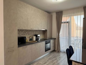 A modern kitchen with a microwave, coffee maker, and oven. - Joy City Stay Mangalia 5 (Timișoara)