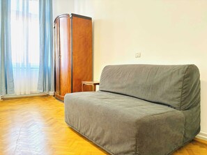 A room with a grey sofa, wooden wardrobe, and a small wooden table. - Joy City Stay  Unirii 2 (Timișoara)