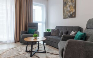 Un salon moderne avec un canapé gris, un fauteuil assorti, une petite table ronde et une plante en pot.