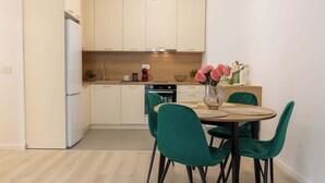 A modern kitchen with a dining area, including a table with chairs and a vase of flowers.