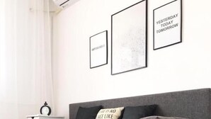 Una sala de estar moderna con un sofá gris, un taburete redondo pequeño y tres carteles motivacionales enmarcados en la pared.