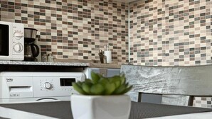 Una cocina con microondas, cafetera y una planta en maceta sobre la encimera.
