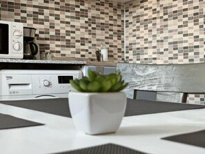 Eine Küche mit Mikrowelle, Kaffeemaschine und einem Blumentopf auf der Arbeitsfläche.