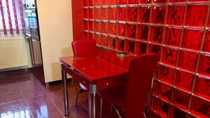 A red table and chairs in a room with a red patterned wall and a radiator. - Joy City Stay Calea Timisoarei 4 (Timișoara)