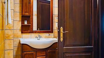 A bathroom with a wooden vanity, a sink, a mirror, a shower, and a toilet.