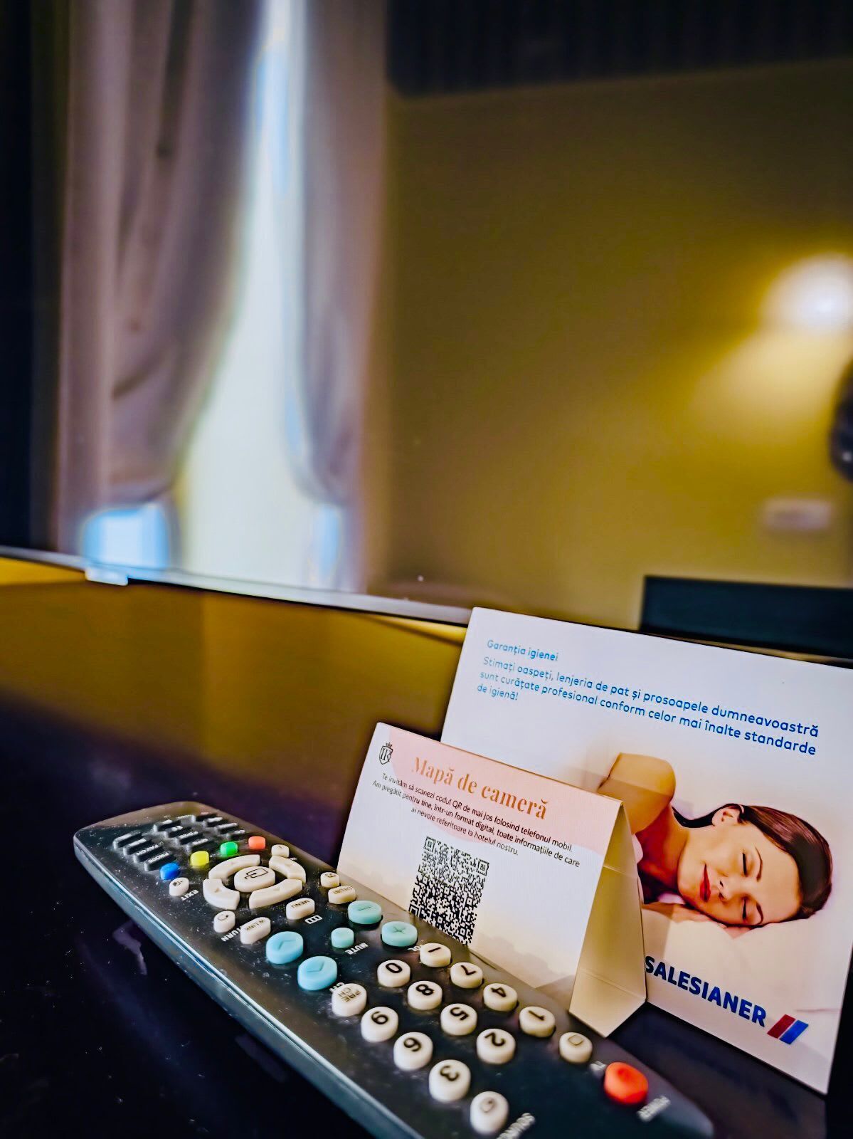 A remote control, a business card, and a QR code on a table.