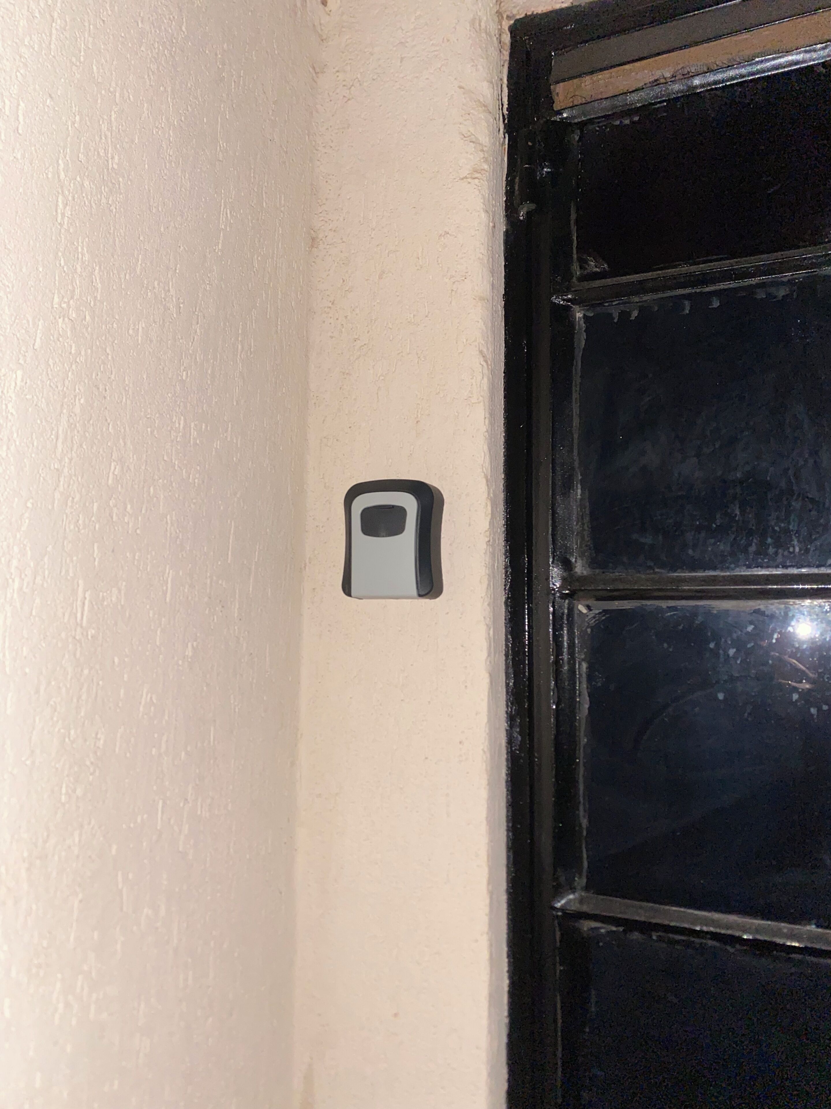 Une porte dotée d’un judas et d’un petit appareil d’interphone rectangulaire fixé au mur.