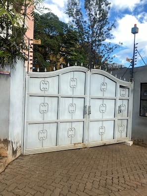 A gated entrance with decorative metalwork, a paved pathway, and a building in the background. - Ruaka Karington Studio (Ruaka)