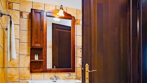 Een badkamer met een houten wastafel, een wastafel, een spiegel, een douche en een toilet.