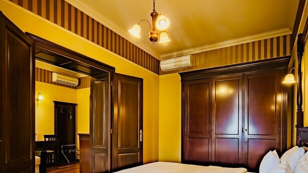 Een slaapkamer met een houten bed, een plafondventilator en een deur naar een eetgedeelte.