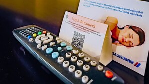 Een afstandsbediening, een visitekaartje en een QR-code op een tafel.